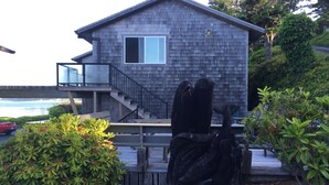 A modern house with a wooden exterior, a balcony, and a staircase leading to the upper floor.