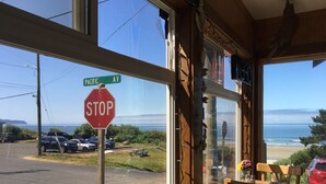 A view from a window overlooking Pacific Avenue, with a stop sign, parked cars, and a beach in the distance.