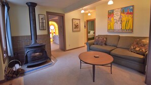 A cozy living room with a fireplace, a sofa, and a coffee table. - Downtown Port Townsend - Hillside Penthouse Vacation Rental (Port Townsend)