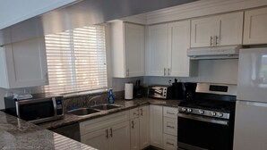 A modern kitchen with white cabinets, granite countertops, a stove, microwave, and a toaster.
