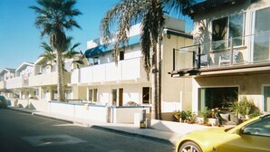 A row of modern, two-story beachfront condos with balconies, palm trees, and a yellow car parked on the street. - Seashore Dr - 12 Bikes, 10 Boards, 8 Wetsuits, 11 Beach Chairs & Beach Toys - (Newport Beach)