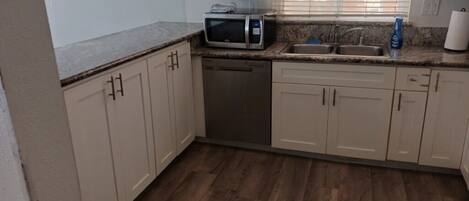 A kitchen with a microwave, dishwasher, sink, and cabinets.