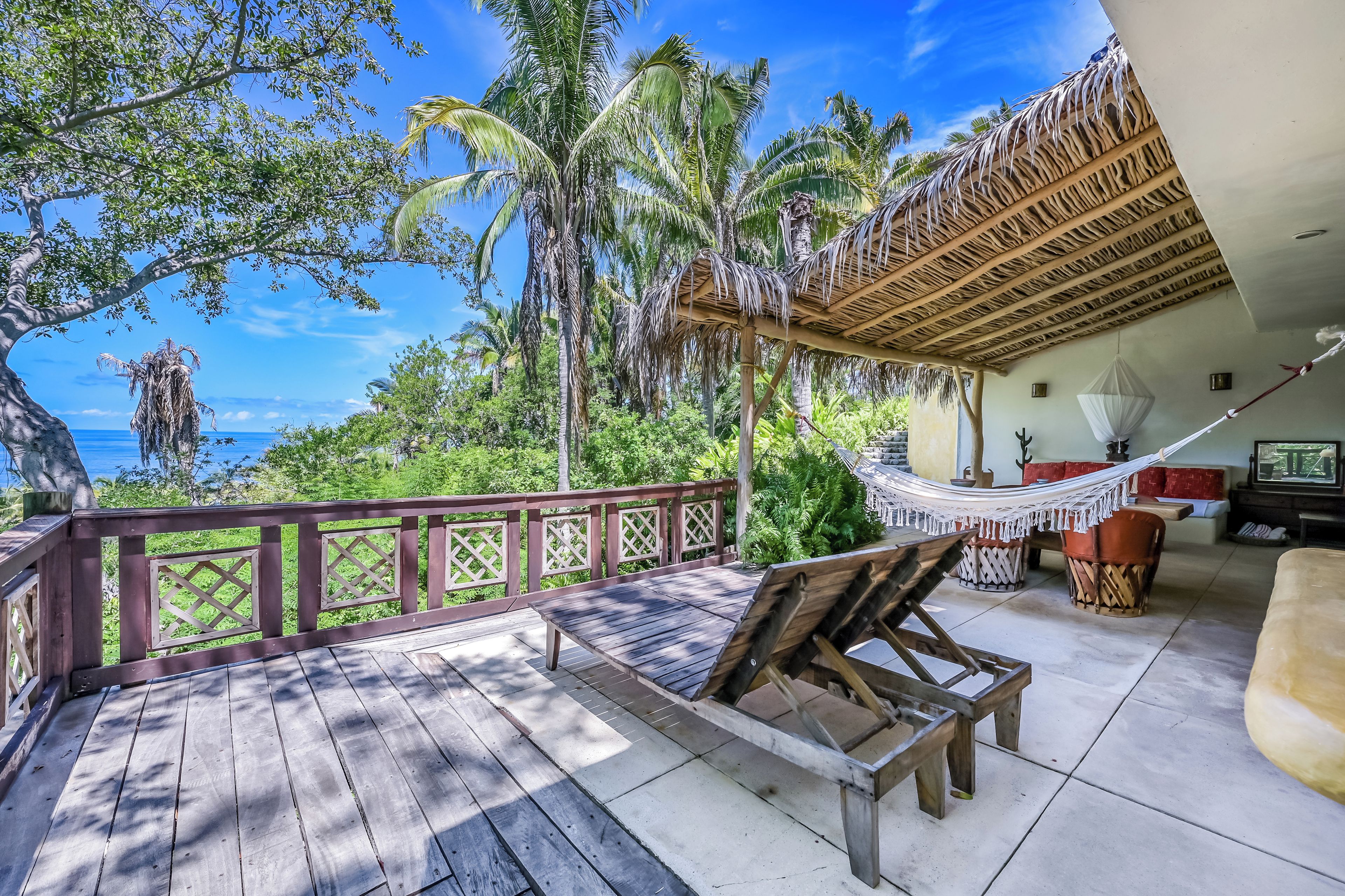 A wooden deck with a hammock, a wooden bench, and a dining area with a table and chairs.