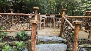 Un puente de madera con escalones que conducen a una zona de estar en un entorno natural.