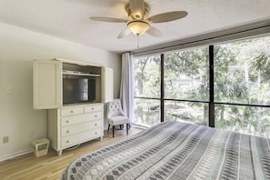 Ein Schlafzimmer mit einem großen Bett, einem Kleiderschrank, einem Sessel und einem Deckenventilator.