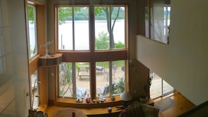 A room with large windows overlooking a deck and water. There are wooden beams, a ceiling fan, and a small table with decorative items. - LAKE HOUSE SOUTH
Waterfront Retreat with DOCKAGE on Susquehanna River & HOT TUB (Pequea)