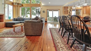 A spacious living room with a large window, a sofa, a coffee table, and a dining area with chairs and a table. - LAKE HOUSE SOUTH
Waterfront Retreat with DOCKAGE on Susquehanna River & HOT TUB (Pequea)
