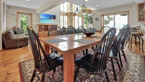 A spacious dining area with a wooden table and chairs, a television on the wall, and large windows offering a view of the outdoors. - LAKE HOUSE SOUTH
Waterfront Retreat with DOCKAGE on Susquehanna River & HOT TUB (Pequea)