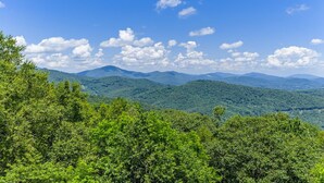 A mountainous landscape with dense green foliage and a clear blue sky.