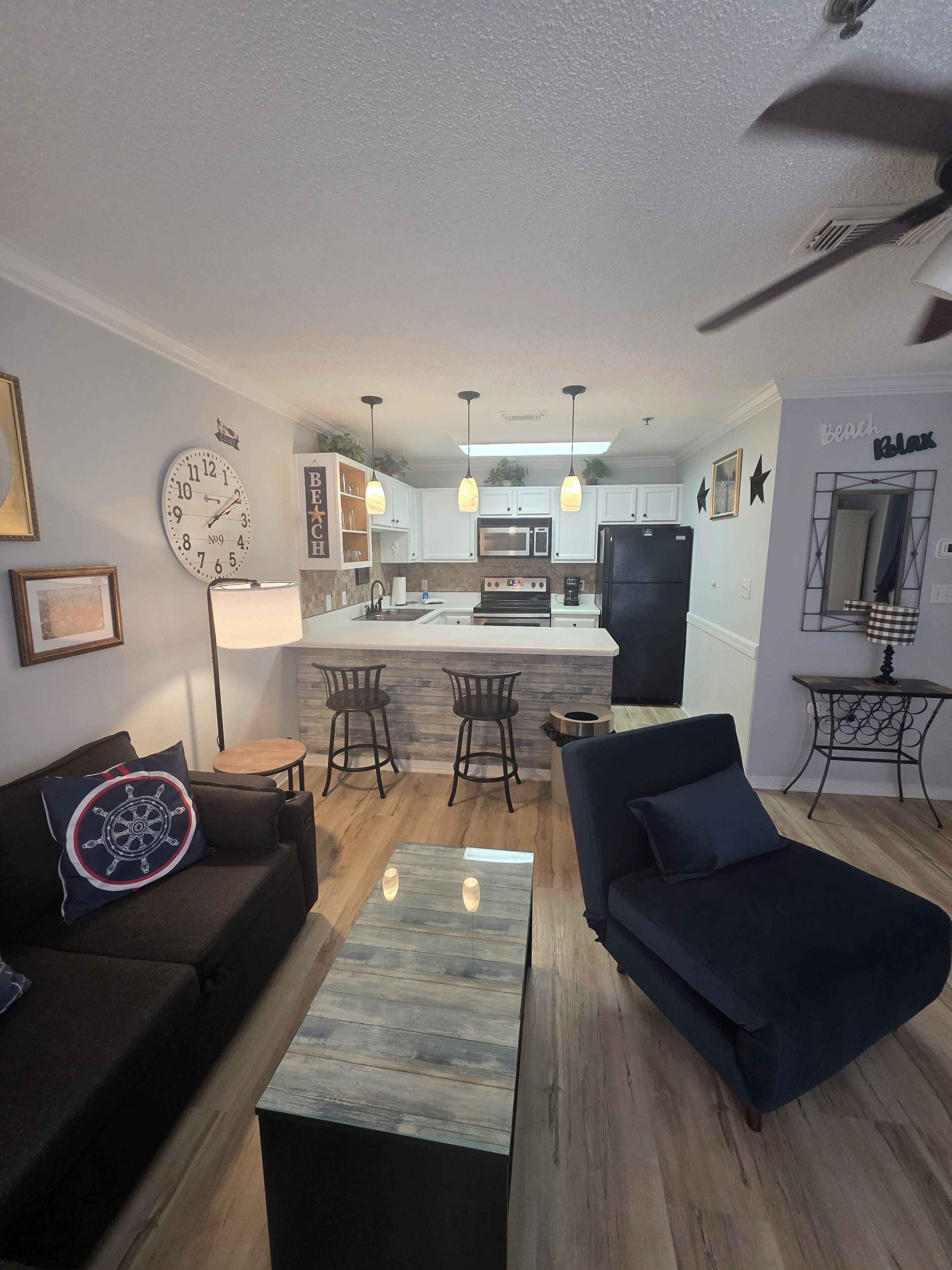 A modern living room with a sofa, a coffee table, and a dining area with a kitchen in the background.