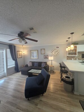 A modern living room with a sofa, a coffee table, a dining area with bar stools, and a kitchen with pendant lights. - Ground floor! Private Balcony!
Beautifully located!! 1 bedroom
3 Sleeping Areas (Destin)