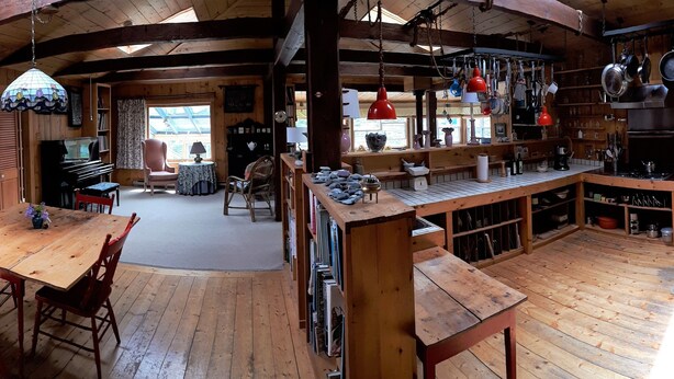 A wooden cabin interior with a dining area, kitchen, and seating space. - Experience Peace And Tranquility At Charming Cottage In Small Fishing Community. (Trinity T.B.)