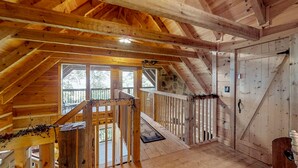 Un interior de madera con techo inclinado, una escalera y vistas amplias a través de grandes ventanales.
