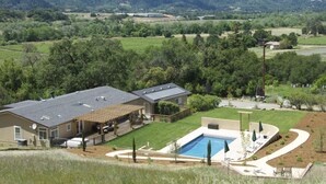 Ein Haus mit großem Garten, Schwimmbad und Blick auf die umliegenden Hügel.