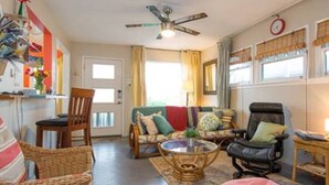 Ein gemütliches Wohnzimmer mit einer Couch, Sesseln, einem Couchtisch und einem Deckenventilator.
