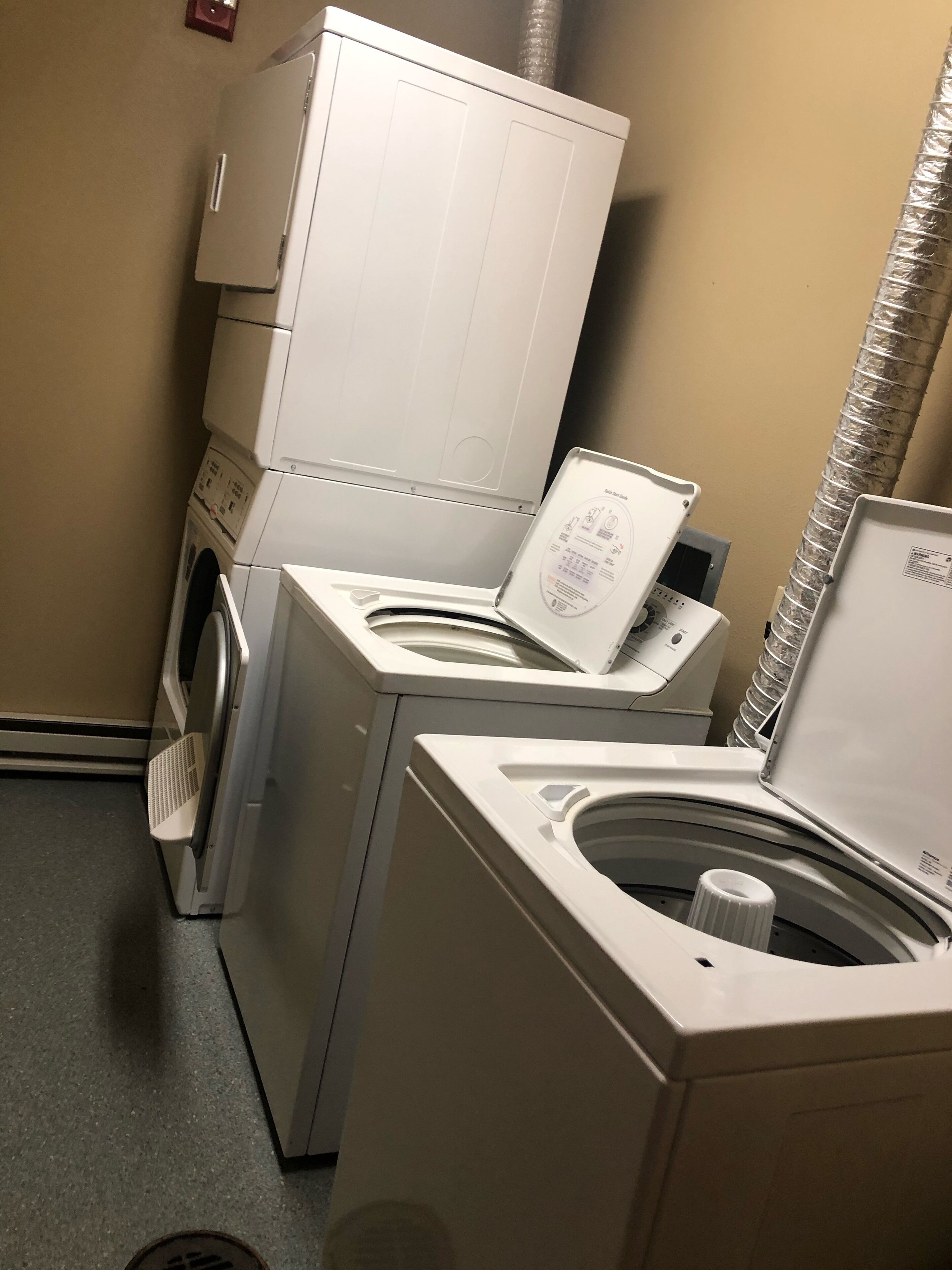 A laundry area with a front-loading washer and dryer, a control panel, and a vent.