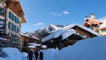Un village de montagne enneigé, avec des bâtiments en bois et un ciel d’un bleu limpide.