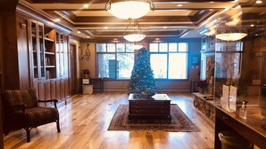 Ein geräumiges Wohnzimmer mit Holzböden, einem großen Weihnachtsbaum und einem Kamin.