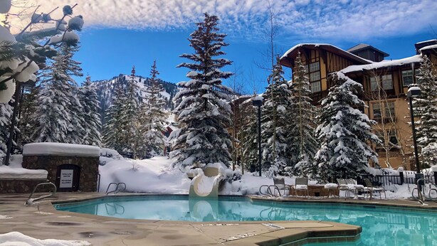 Ein Poolbereich mit schneebedeckten Bäumen und einem Gebäude im Hintergrund.