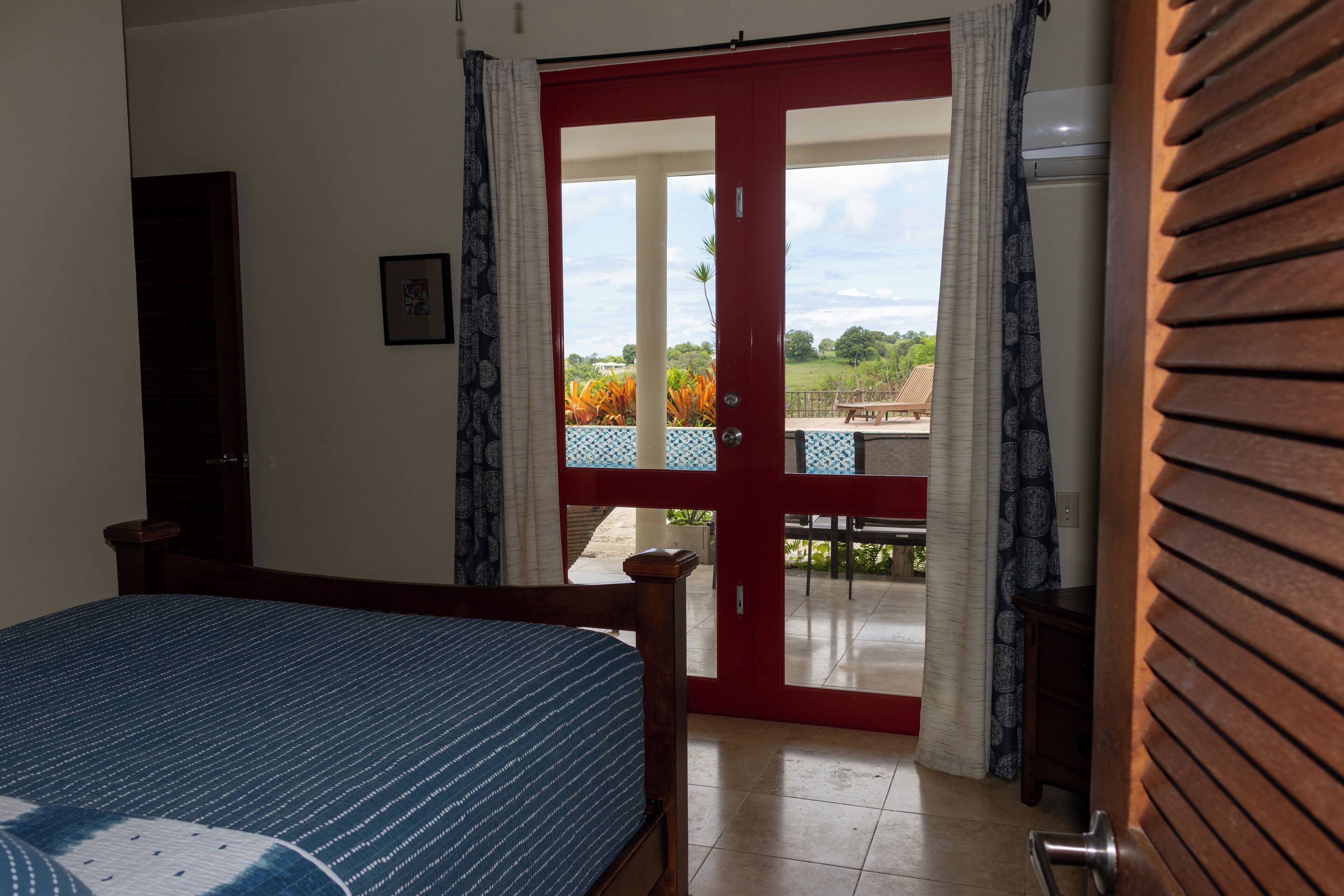 Un dormitorio con cama, una puerta que da a un balcón y vistas al exterior.