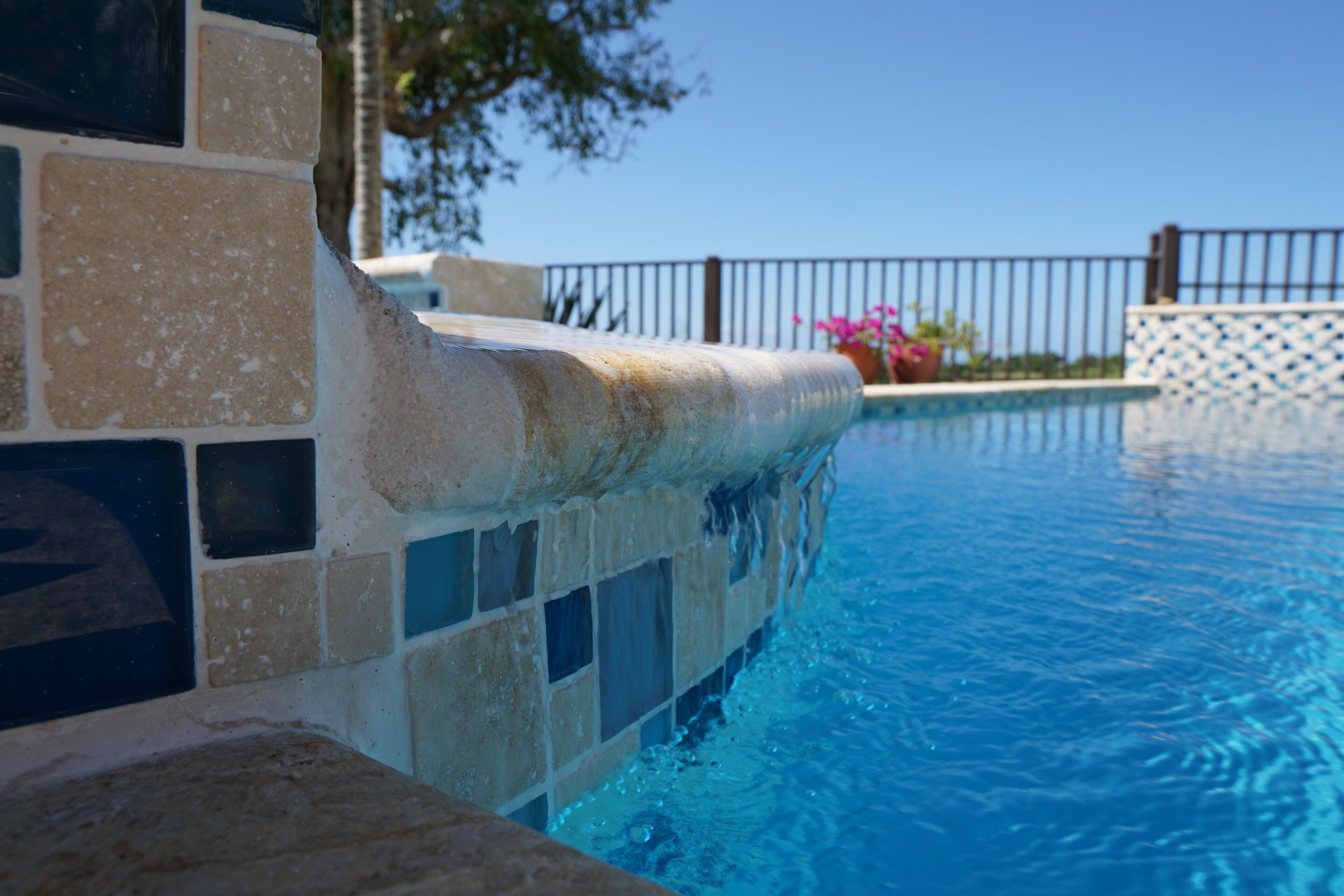 A swimming pool with a tiled edge and a metal fence in the background.