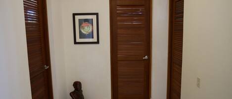 A hallway with wooden doors, a framed picture on the wall, and a sculpture on the floor.