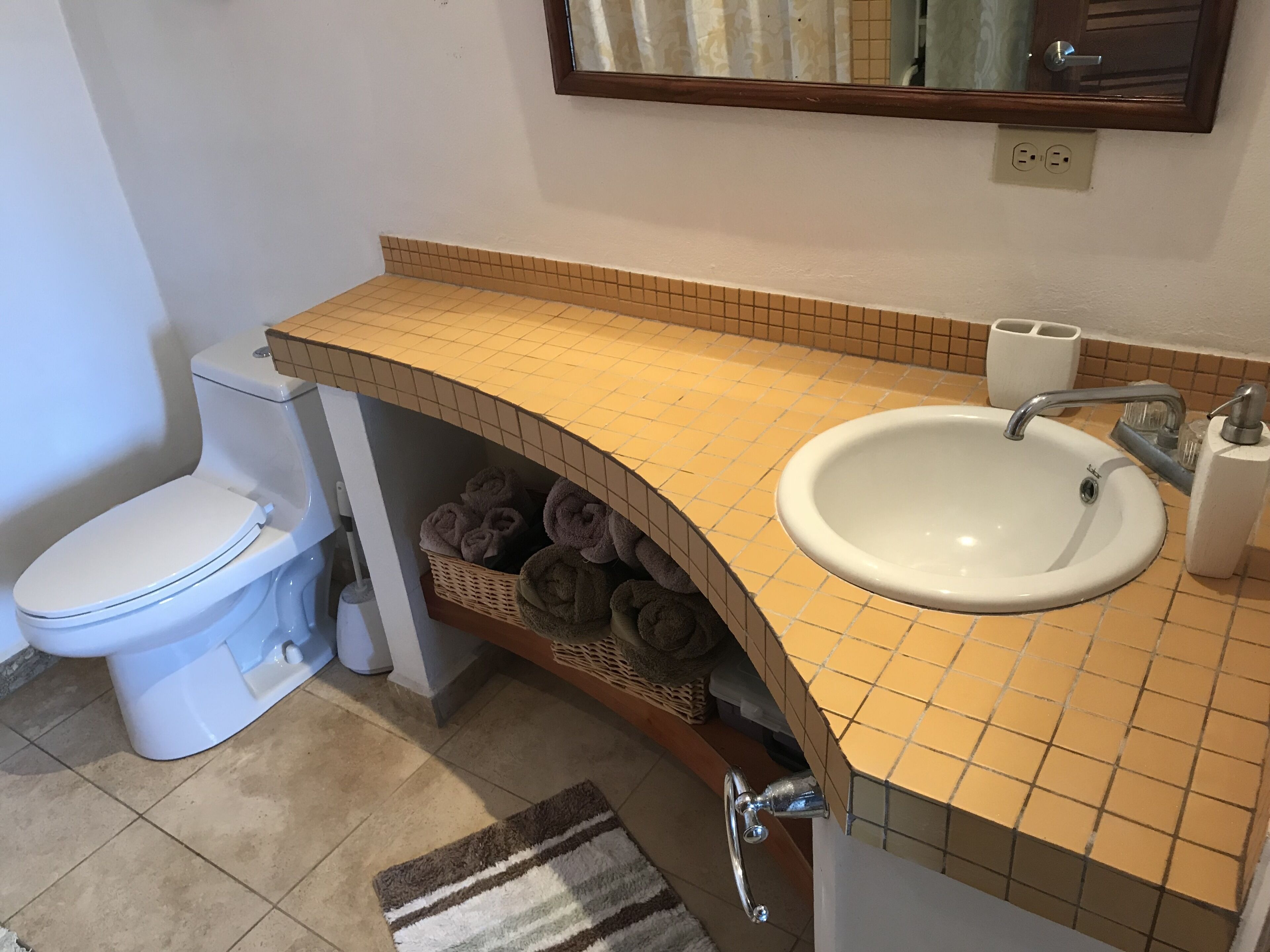 A bathroom with a white toilet, a sink with a mirror above it, and a towel rack with towels.