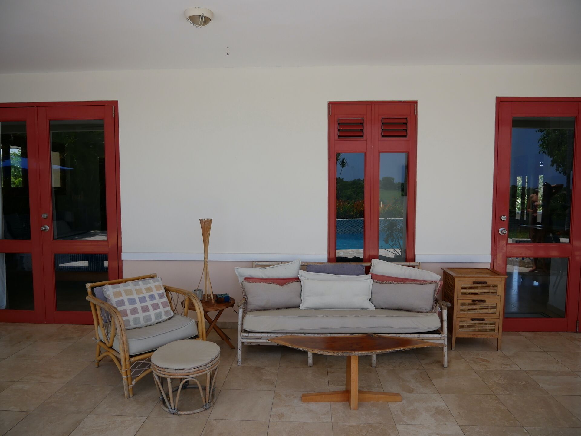 A room with a sofa set, a small round table, and a wooden cabinet. There are two red doors with glass panels.