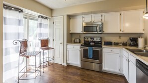 A kitchen with white cabinets, stainless steel appliances, and a window with striped curtains. - A Renovated 3 Bedroom, 2.5 Bath Townhouse In Downtown Lexington. (Lexington)