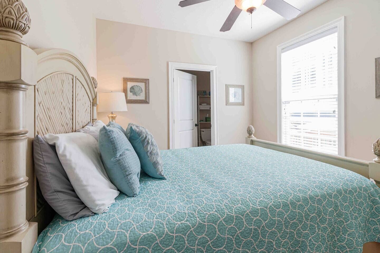 A bedroom with a bed, a nightstand, a ceiling fan, a window with blinds, and a door leading to a closet.