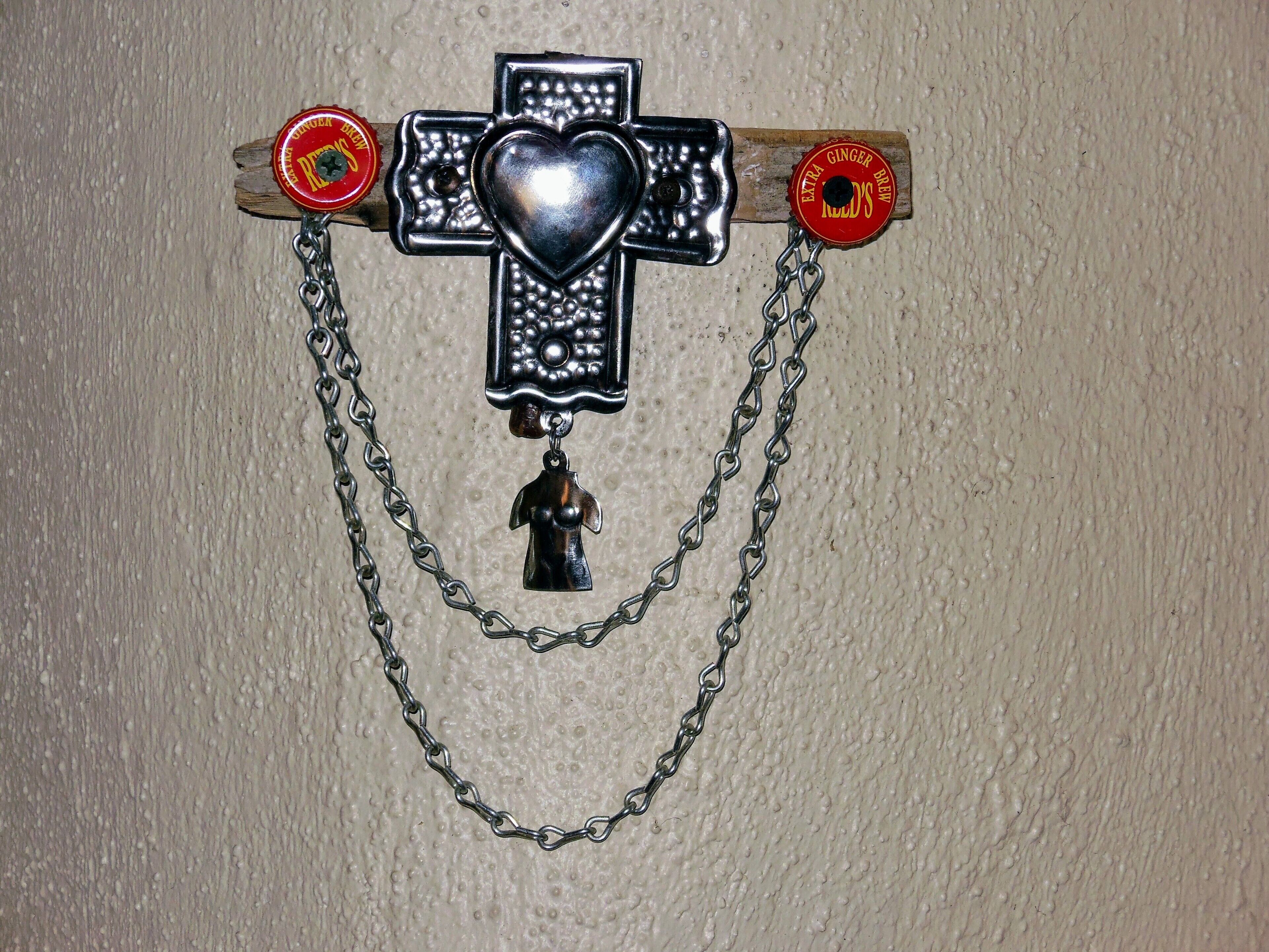 Un pendentif en forme de croix, orné d’un cœur et d’une figurine suspendue à une chaîne.