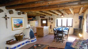 Un interior rústico con una mesa de comedor de madera, un sofá y una zona de cocina con refrigerador y estufa.