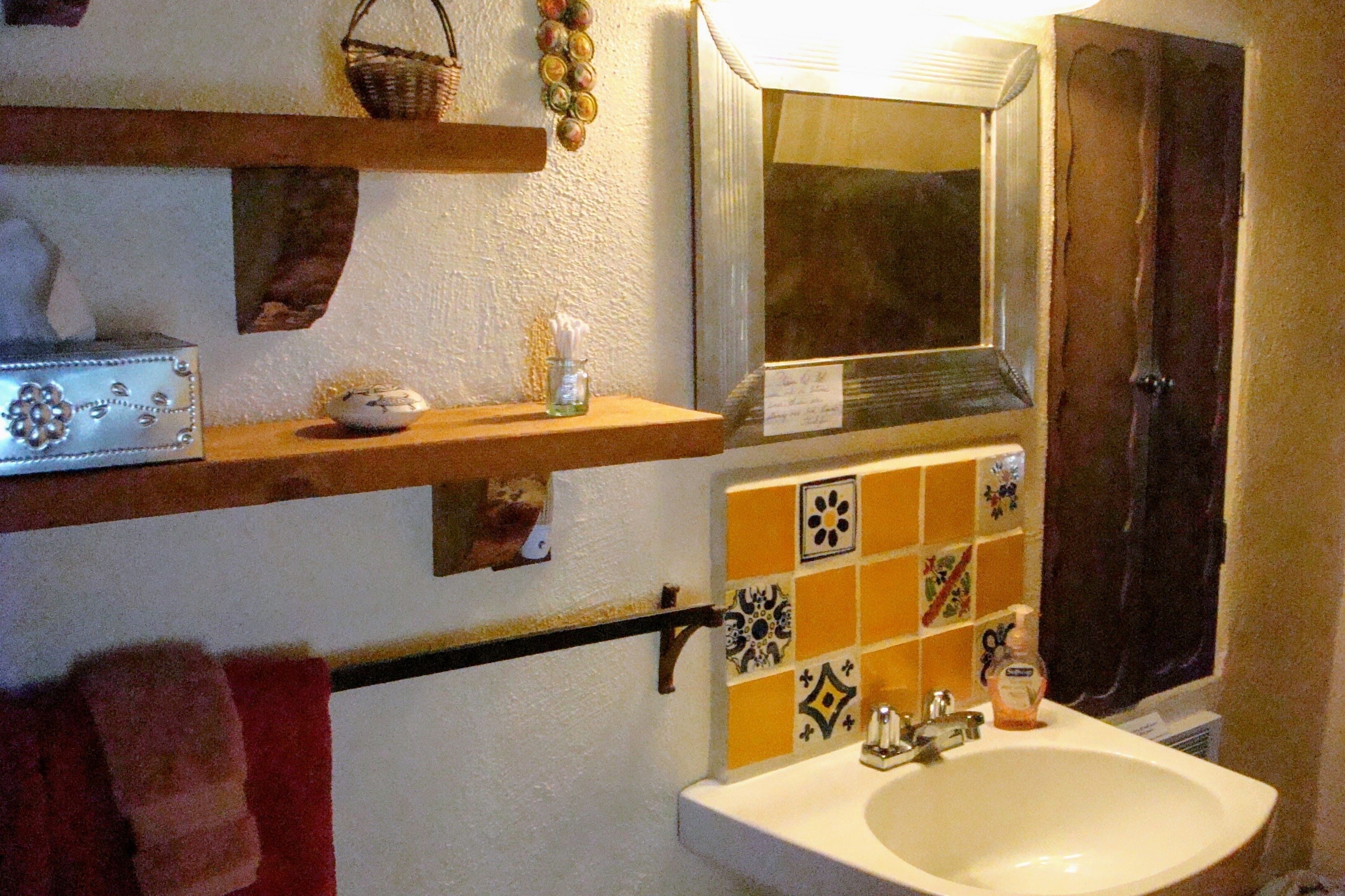 Un baño con lavamanos, espejo y azulejos decorativos.