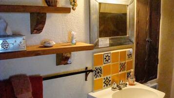 Un baño con lavamanos, espejo y azulejos decorativos.