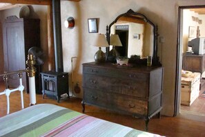 A room with a bed, a dresser, a mirror, a lamp, and a small table.