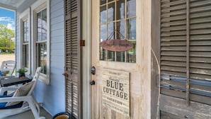 Eingang eines hölzernen Häuschens mit einem Schild, auf dem 'Blue Cottage Vacation' steht.