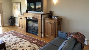 A living room with a fireplace, a sofa, a rug, and a bookshelf. - Allegra Villa Alla Spiaggia  - See & Hear Ocean - Luxurious (Santa Cruz)