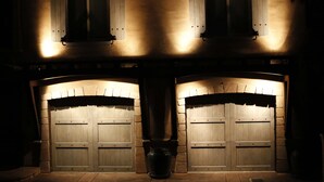A building with two large wooden garage doors, a stone wall, and a potted plant in front. - Allegra Villa Alla Spiaggia  - See & Hear Ocean - Luxurious (Santa Cruz)