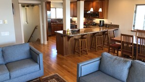 A spacious living area with a large island, wooden bar stools, and a dining table with chairs. - Allegra Villa Alla Spiaggia  - See & Hear Ocean - Luxurious (Santa Cruz)