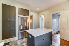 A modern kitchen with a stainless steel refrigerator, dark cabinets, and a white countertop. - Queen Ann Historic Mansion (Covington)