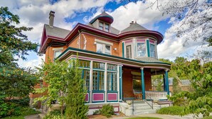 A Victorian-style house with a wrap-around porch, large windows, and a turret. - Queen Ann Historic Mansion (Covington)