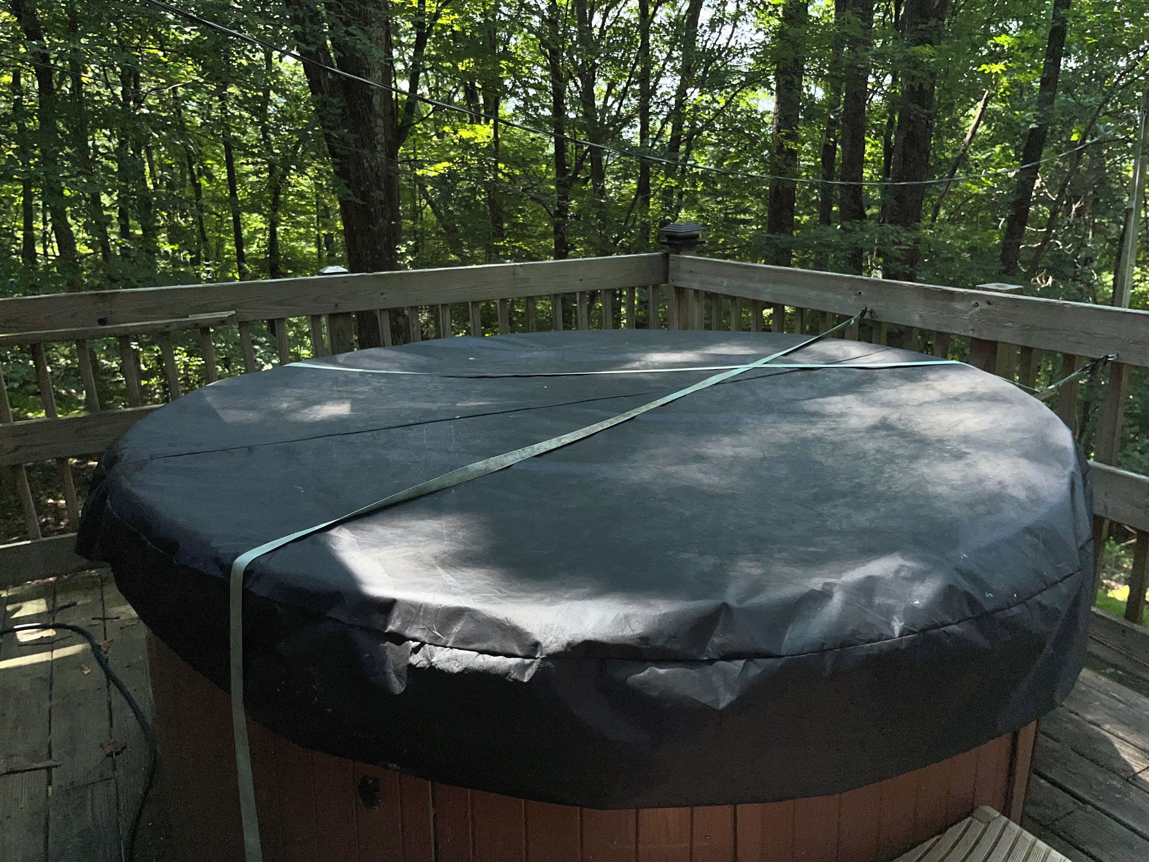 Un espacio de descanso al aire libre con mesa cubierta, rodeado por una terraza de madera y abundante follaje.