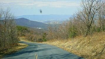 A rural road with a clear view of distant mountains and sparse vegetation.