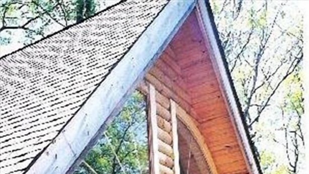 Une cabane en rondins dotée d’une grande fenêtre et d’une porte en bois.