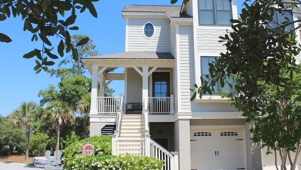 A two-story house with a balcony, a garage, and a stop sign in the foreground. - Designer Saltmarsh Townhome! Neighborhood Pool! Great Location! Amenity access included! (Seabrook Island)