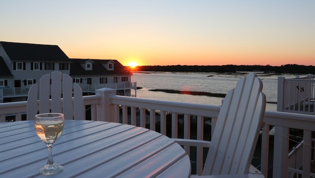 A sunset view from a balcony with a glass of wine on a table. - Monkey Sea, Monkey Dune ~ Top floor, End unit; Sound and Ocean view (Ocean Isle Beach)