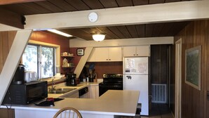 A kitchen with a central island, wooden chairs, a refrigerator, and a clock. - Free Arcade Room- Great views-1/2 Mi Ski Slopes, 3 Mi. Dwntwn (Gatlinburg)