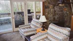 A cozy living room with patterned furniture, a stone fireplace, and a patio with a grill. - Free Arcade Room- Great views-1/2 Mi Ski Slopes, 3 Mi. Dwntwn (Gatlinburg)
