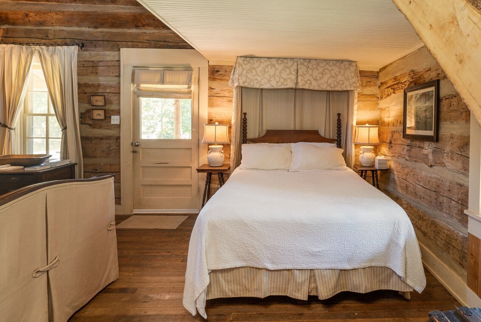 Ein gemütliches Schlafzimmer mit einem großen Bett, Holzwänden, einer Tür, die nach draußen führt, und zwei Nachttischlampen.