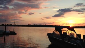 En båd ligger til anker i en lysthavn med solnedgang i baggrunden.